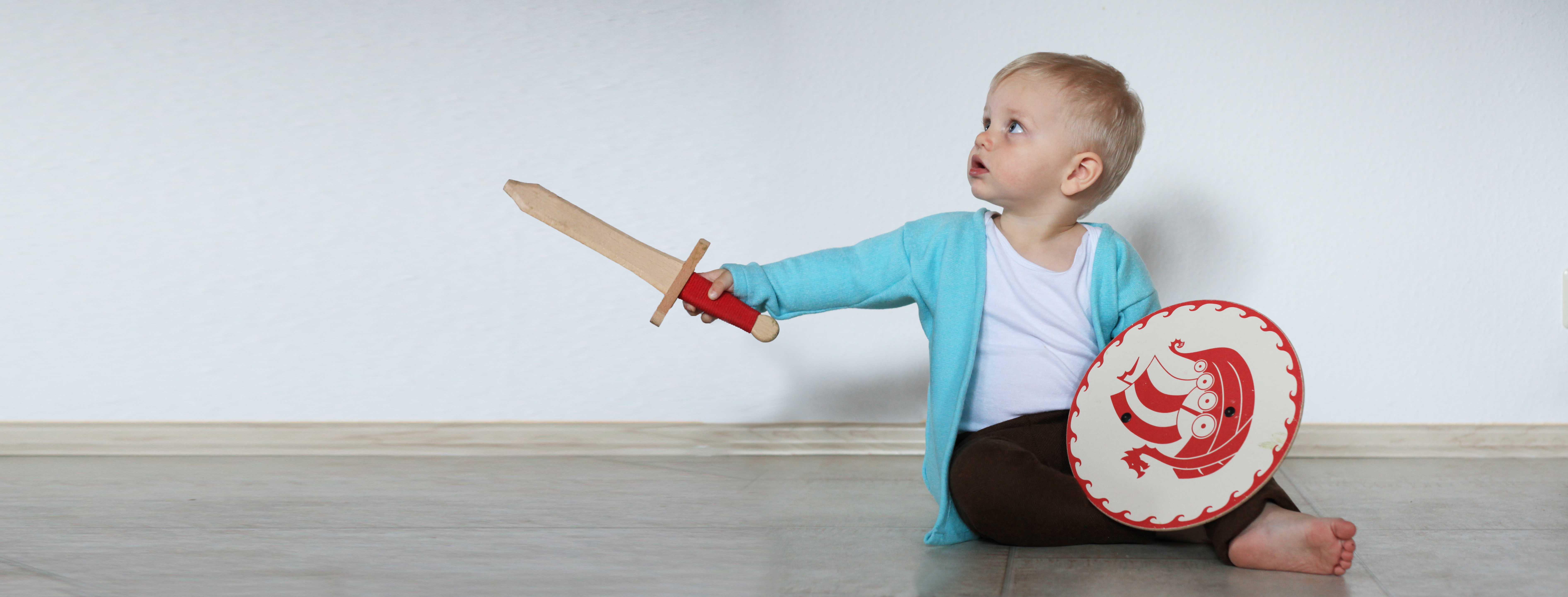 Kleinkind mit Schild und Schwert in der Hand