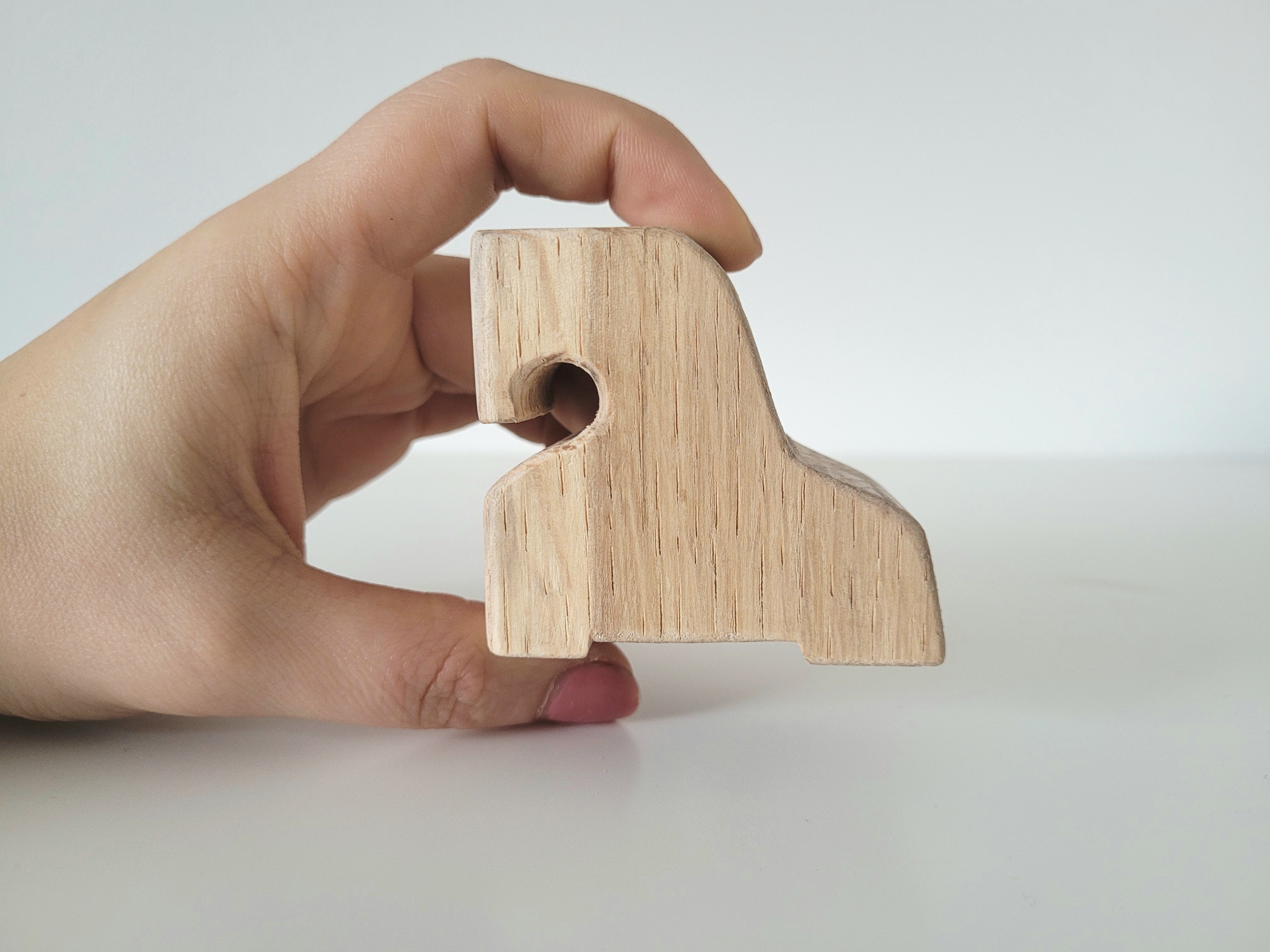Eine Hand hält ein Holzfpferdchen zur besseren Darstellung der Größe.